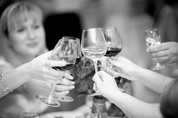 Closeup black and white photo of clinking glasses with wine at restaurant