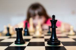 Young white child playing a game of chess on large chess board.