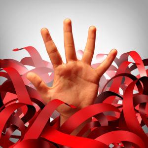 Bureaucratic red tape problem as a human hand tangled in bureaucracy and regulations as a business concept and symbol of government gridlock or corporate regulatory confusion.