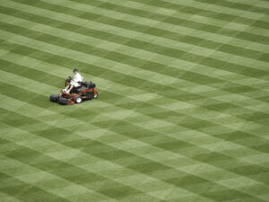 A workman mows a baseball field.