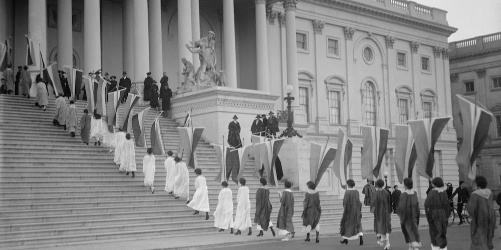 Woman Suffrage demonstration with banners at the U.S. Capitol in 1917. View of Procession ascending Capitol steps.