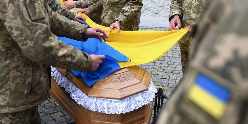 Servicemen cover the coffin of Ukrainian serviceman who was killed during Russia's invasion of Ukraine with a Ukrainian flag during his funerals