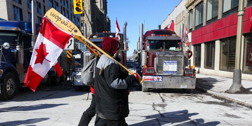 People carry canoe paddles with Canadian flags, as truckers and supporters continue to protest the coronavirus disease (COVID 19) vaccine mandates, in Ottawa, Ontario, Canada, February 14, 2022. REUTERS/Lars Hagberg