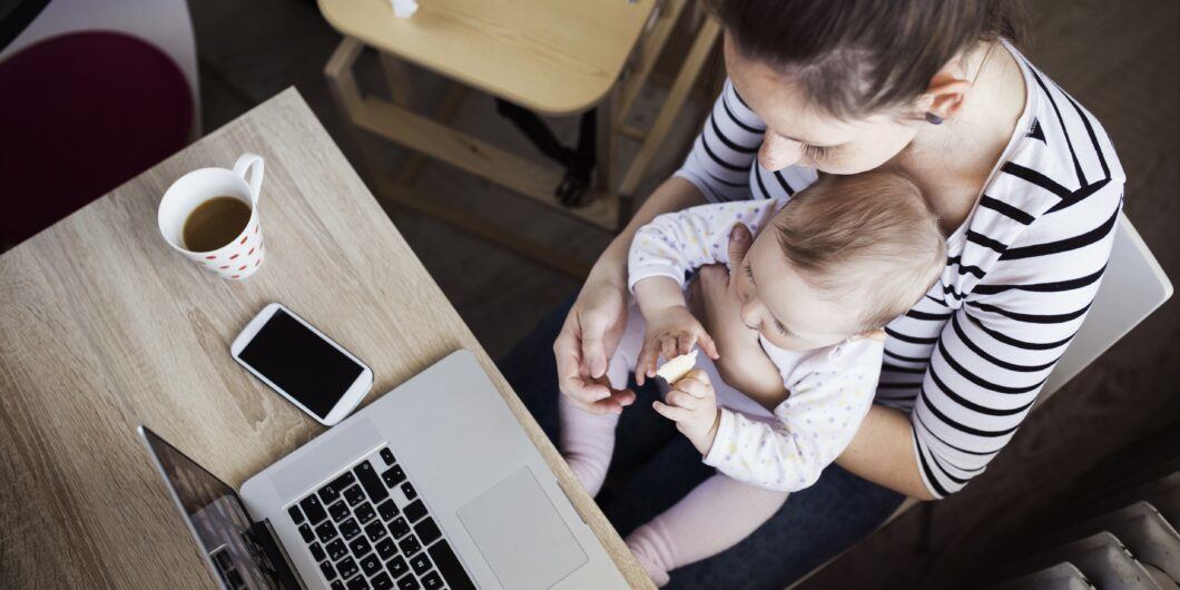Young mother in home office with computer and her daugher