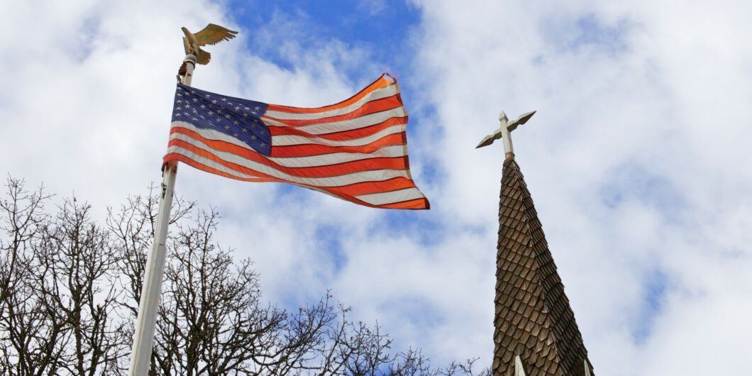 American flag flying next to a church steeple 1060x530.jpg