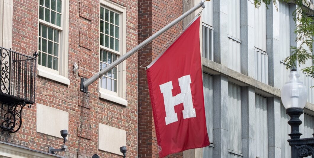 Cambridge, MA, USA   June 29, 2022: Harvard flag is seen outside the Harvard Cooperative Society (the Coop), a collegiate bookstore on the Harvard University campus in Cambridge, Massachusetts.