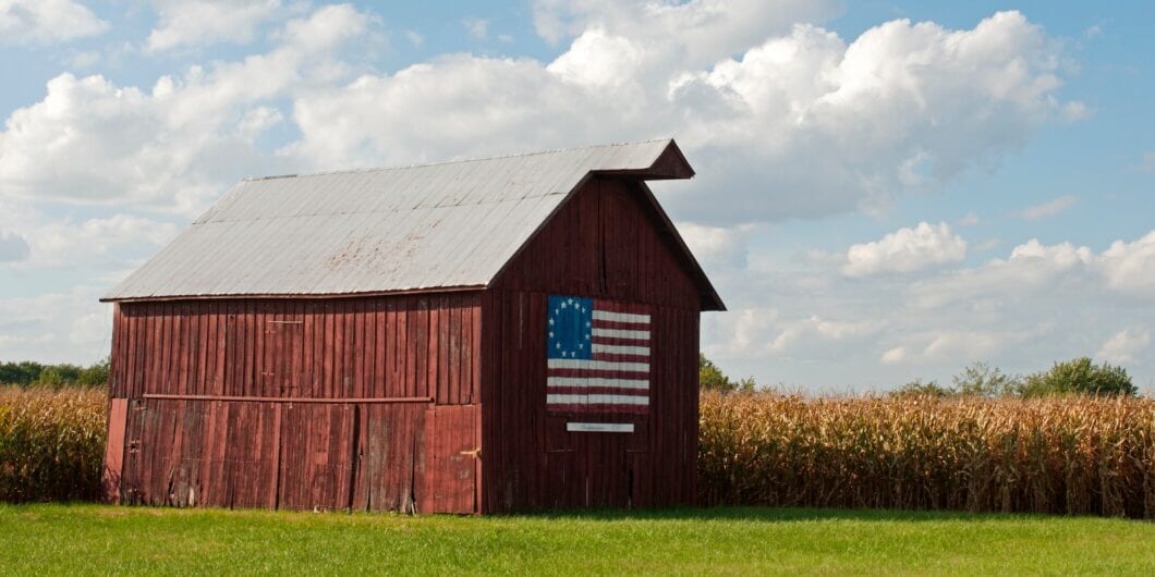 Nilwood, IL, USA   Oct. 1, 2019: A weathered wooden barn with a painting of the 13 star Betsy Ross flag (an early American flag design) stands near cornfields along old Route 66 in Nilwood, Illinois.